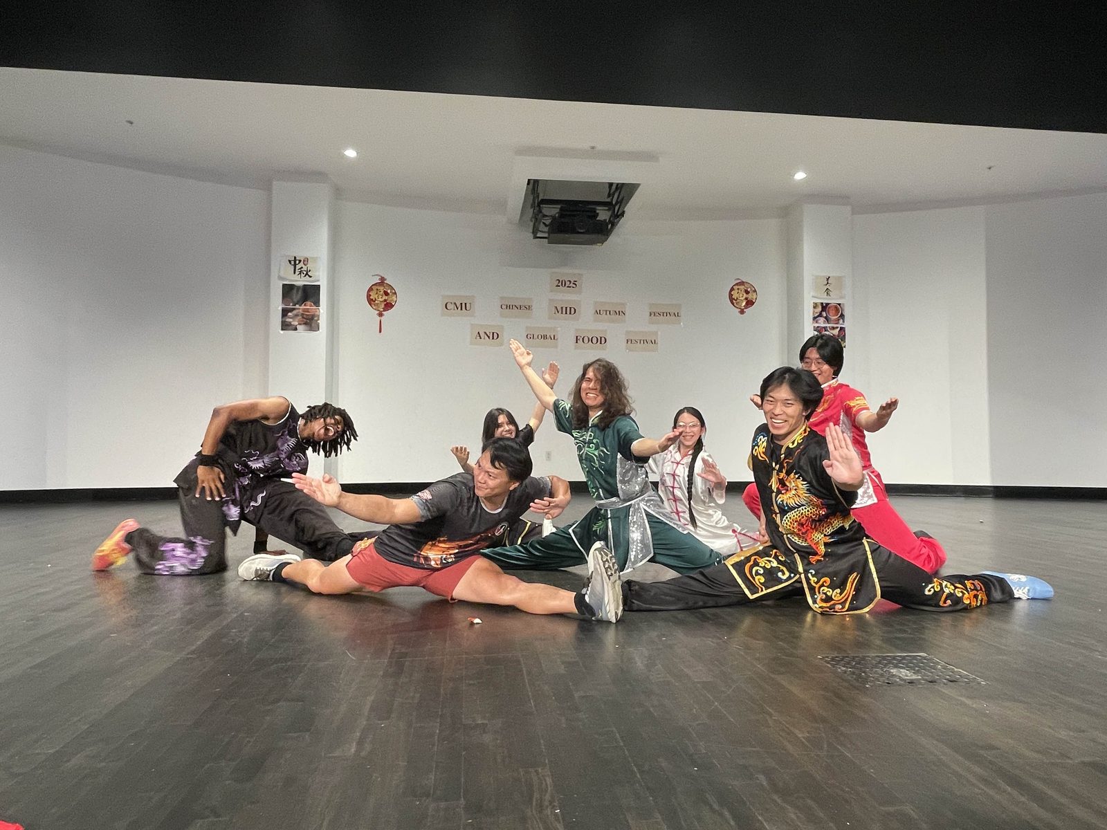 The group in a final pose on the floor, some kneeling and some in splits with arms raised
