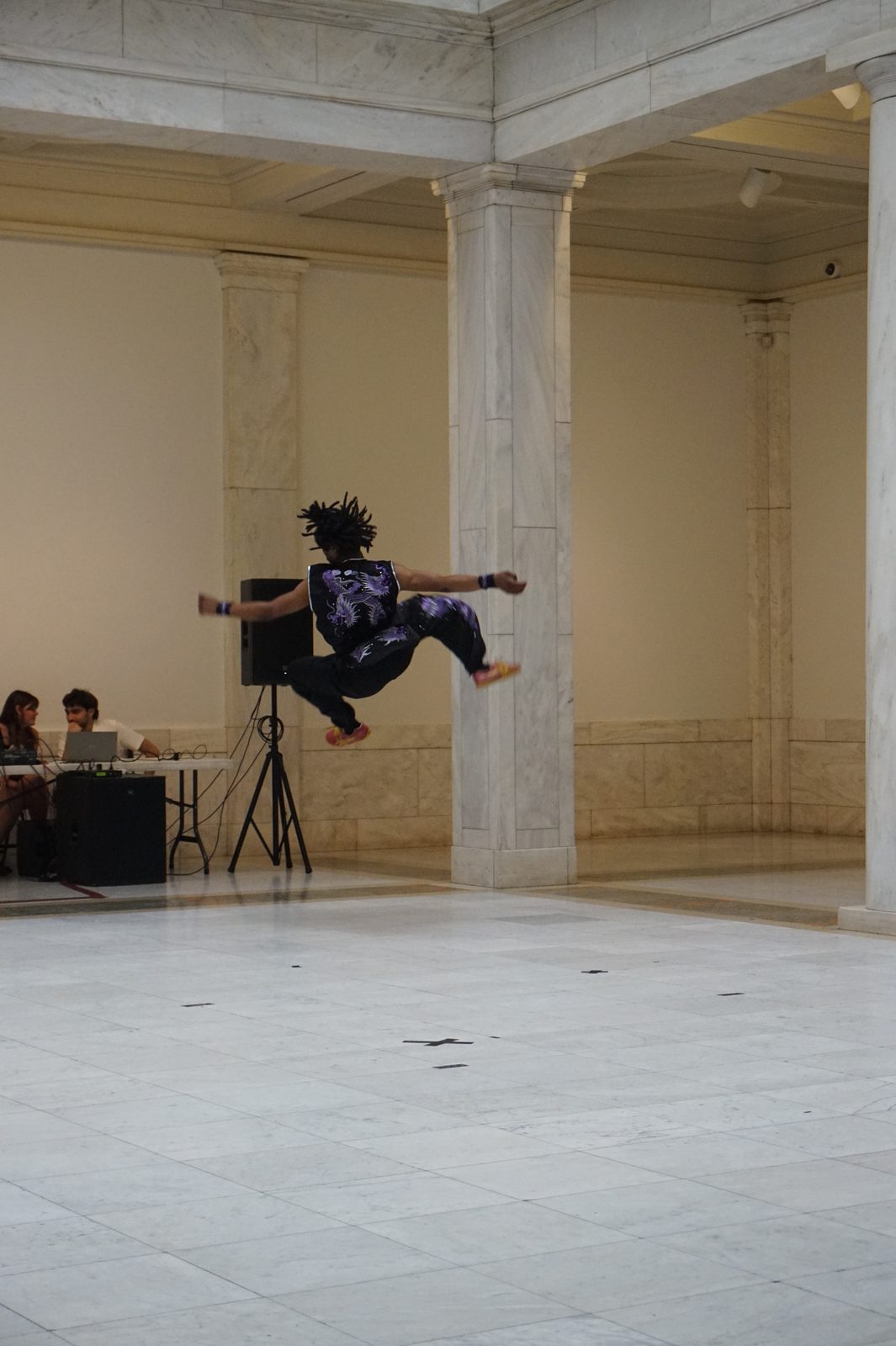 A performer captured mid-air in a jumping kick in the museum hall